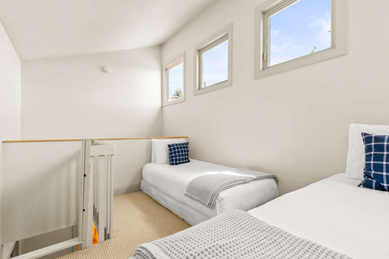 Two cozy twin beds in a bright, airy loft space with windows that bathe the room in natural light—perfect for your peaceful, restful nights.