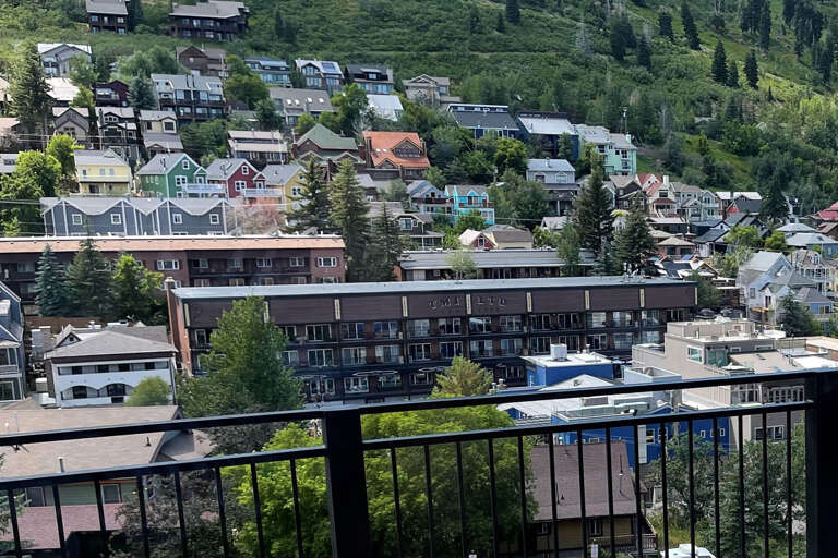 Hillside neighborhood views with colorful homes nestled among evergreens surround this property, offering a charming mountain town setting.