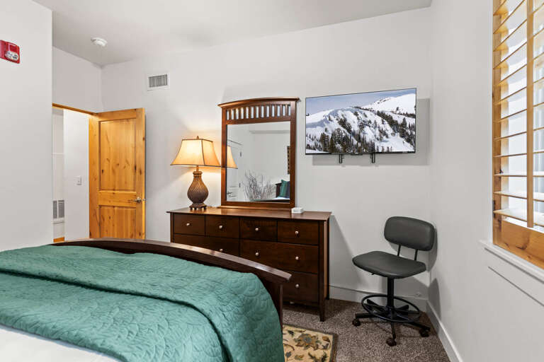 Unwind in your cozy bedroom with mountain views on the TV, warm wood tones, and soft lighting for your perfect getaway.