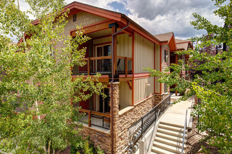 A modern mountain retreat featuring rustic charm and private balconies, framed by towering aspens and nestled within a peaceful residential neighborhood.