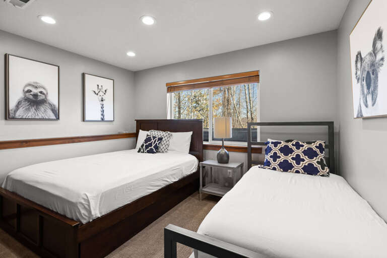 Rest peacefully in this cozy bedroom featuring two comfortable beds dressed in crisp linens. Warm wood accents and playful wildlife art create a welcoming retreat where you'll wake up to serene treetop views through your window.