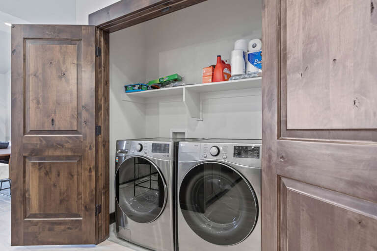 Your in-unit washer and dryer make packing light a breeze, tucked neatly behind rustic wood cabinetry with convenient storage above for laundry essentials.
