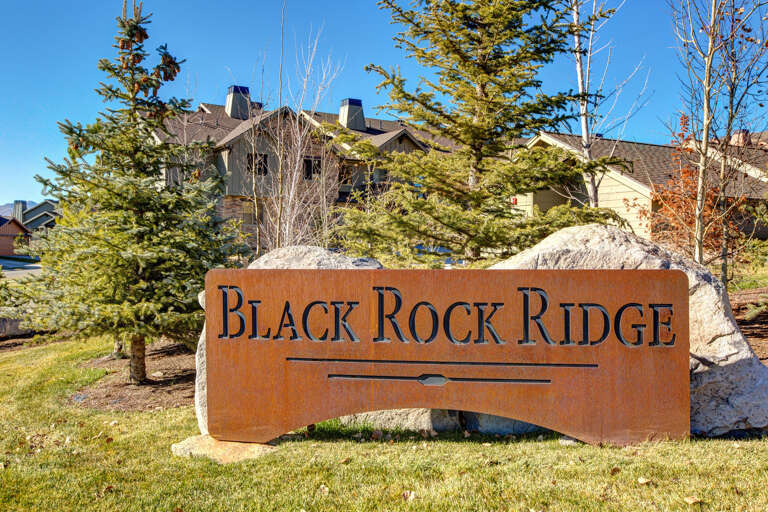 Black Rock Ridge property sign marks the entrance to this mountain community, surrounded by mature evergreens and natural stone features.