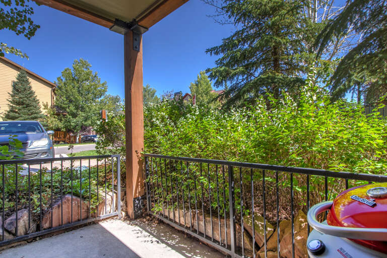 This covered patio overlooks a quiet residential street lined with mature trees and greenery. Off-street parking is conveniently located nearby.