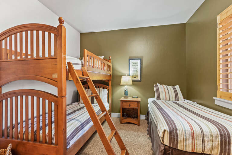Your cozy bedroom features warm wood bunk beds and a comfortable twin, perfect for families or groups. Soft lighting and cheerful striped linens create a welcoming retreat for restful nights.