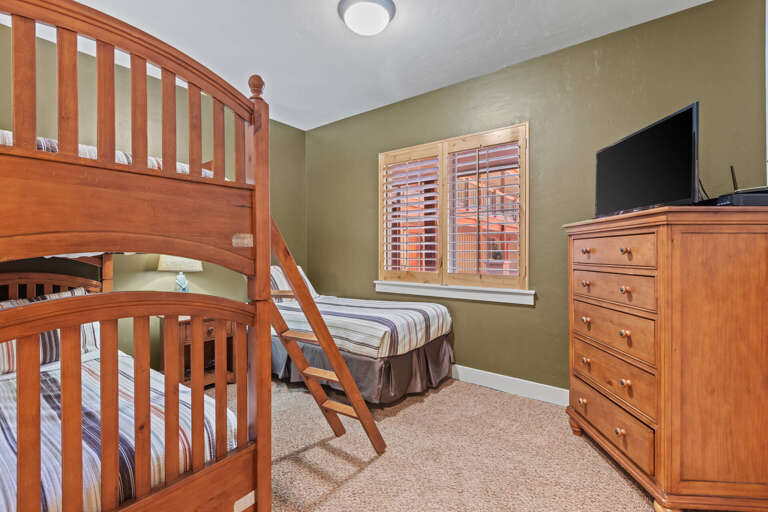 Your cozy bedroom features a sturdy bunk bed and additional sleeping space, perfect for families or groups traveling together. The warm wood furnishings and soft carpeting create a comfortable retreat after your adventures.