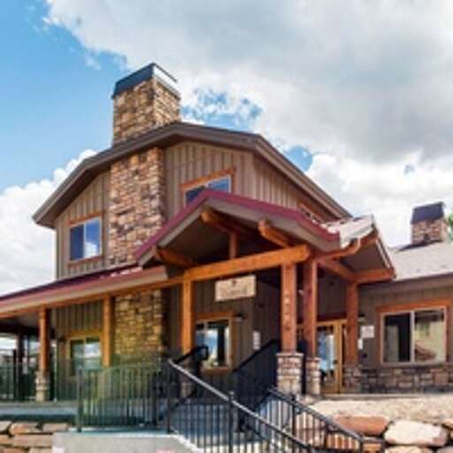 A distinctive lodge-style entrance with warm stonework and a welcoming red awning marks your arrival to this mountain property.