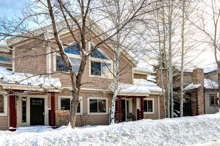 Multi-unit vacation property exterior featuring modern mountain architecture with distinct entrances and white birch trees blanketing the snow-covered grounds in winter.