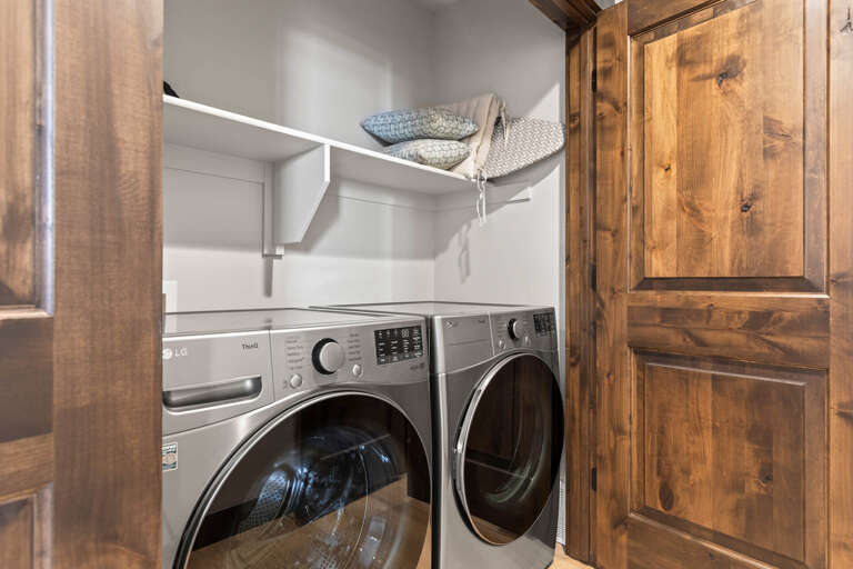 A modern washer and dryer pair nestled in a dedicated laundry closet with clean shelving, making it easy for you to keep your favorite vacation clothes fresh throughout your stay.
