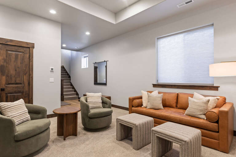 Settle into plush seating where warm leather and soft fabrics invite you to relax. Natural light filters through the window, highlighting the inviting space designed for your comfort and quiet moments together.