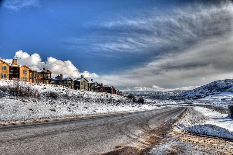 Snow-dusted mountain properties under dramatic winter skies, set against expansive rolling hills blanketed in fresh powder and sweeping alpine vistas.