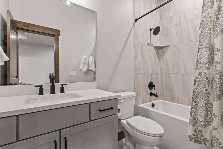 Freshen up in your private bathroom featuring a sleek vanity, wood-accented mirror, and relaxing tub-shower combo with modern finishes.