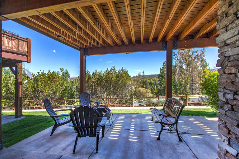 Settle into your private covered patio with sweeping mountain and tree-lined views. Stylish seating invites peaceful mornings and serene evenings under warm wooden beams framing the natural beauty beyond.