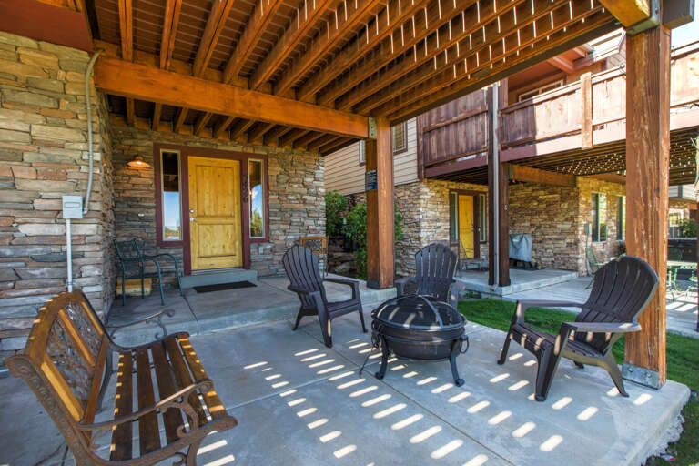 Step outside to your private covered patio, where rustic stone meets warm wood beams. Relax in comfortable Adirondack chairs around the fire pit, perfect for evening gatherings.