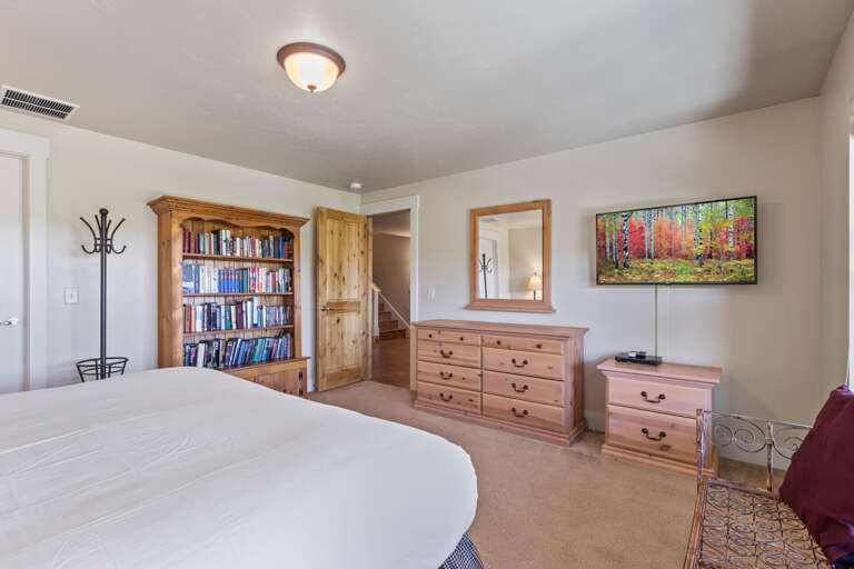 Relax in your spacious bedroom with cozy pine furnishings, a library for evening reading, and a flat-screen TV. Soft neutrals and warm wood tones create a peaceful retreat.