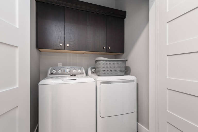 A dedicated laundry nook awaits with a full-size washer and dryer, custom overhead cabinetry, and clever storage to keep your vacation wardrobe fresh and ready.