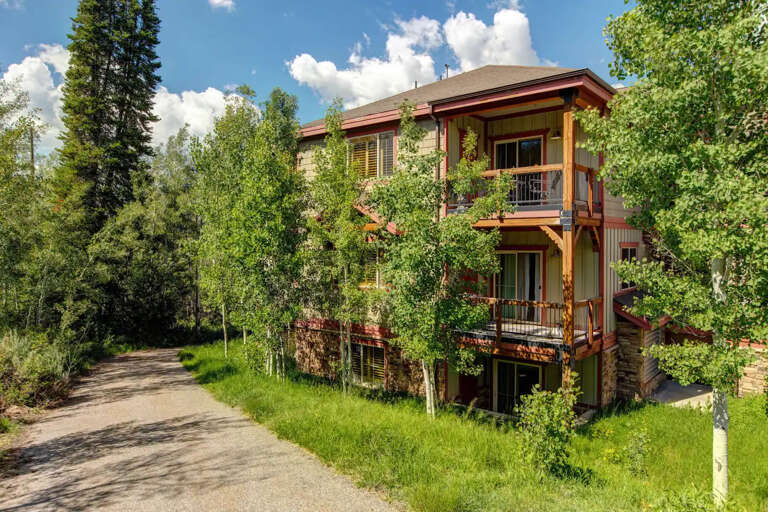 A contemporary mountain home with warm wood accents and spacious balconies sits nestled among aspens and pines, offering a peaceful retreat in a natural setting.