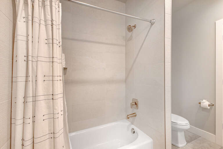 A clean, bright bathroom features a full tub-shower combo with modern fixtures and plenty of space to refresh after your day's adventures.