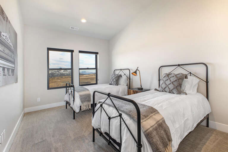 Drift off in plush twin beds with cozy layers and wake to sweeping countryside views through tall windows—a serene retreat for restful mornings.