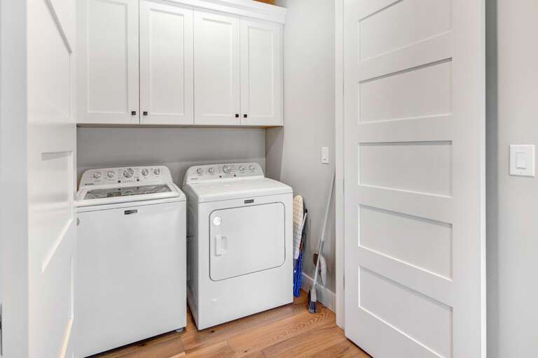 Your vacation stays fresh and easy with this dedicated laundry nook, featuring side-by-side washer and dryer tucked neatly under bright white cabinetry for all your storage needs.