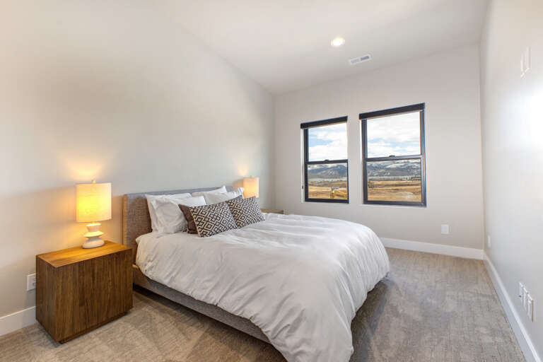 Drift off in this inviting bedroom, where crisp linens meet warm lighting, and twin windows frame stunning mountain vistas that greet you each morning.