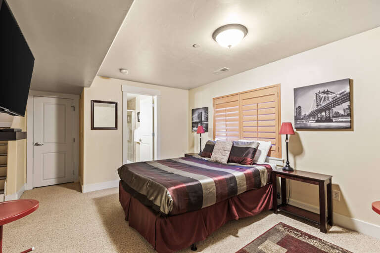 Your cozy retreat awaits with plush bedding in rich burgundy tones, complemented by ambient lighting and elegant urban artwork. Relax in comfort with modern amenities and thoughtful touches throughout your personal sanctuary.