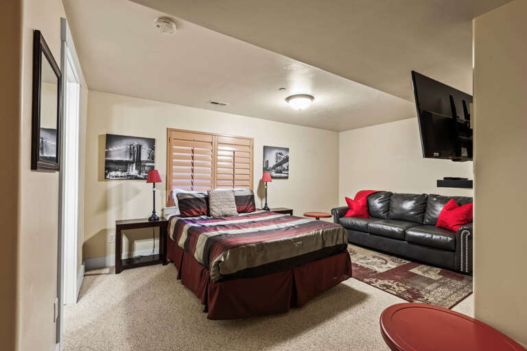 Unwind in your cozy bedroom suite featuring a plush bed, relaxing leather sofa, and flat-screen TV—all set in a warm, inviting space for restful nights.