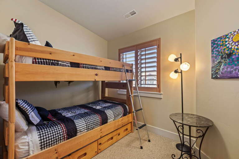 A cozy room with sturdy bunk beds dressed in cheerful plaid bedding, perfect for kids or groups. Warm lighting and cheerful art create a welcoming space where your family can recharge after a day of adventure.
