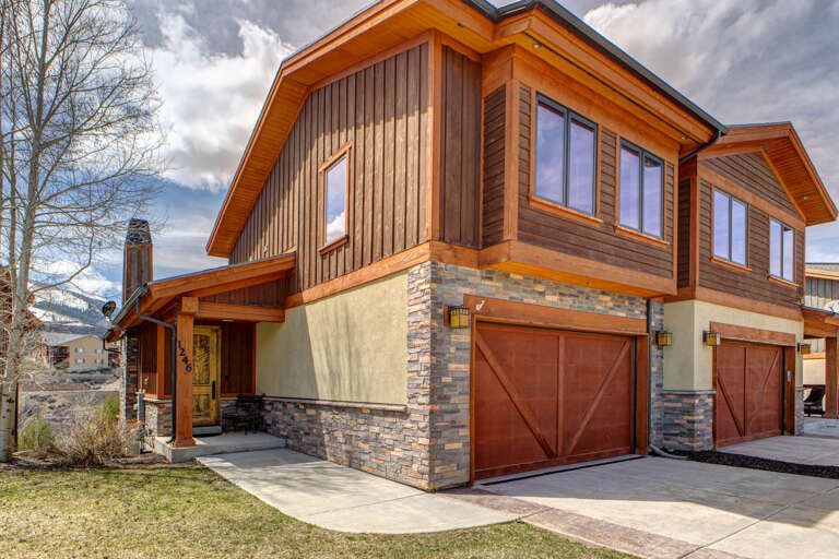 A beautifully crafted mountain retreat featuring warm wood siding, stone accents, and modern design, nestled in a peaceful residential area near scenic mountain views.