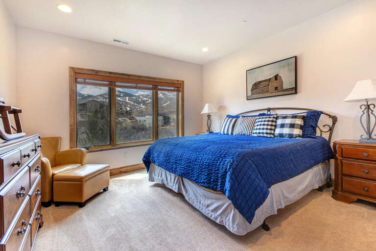 Wake up to stunning mountain views from your plush bed dressed in cozy blue linens. Your bedroom's large windows frame the peaks, while warm wood accents and thoughtful furnishings create your perfect retreat.