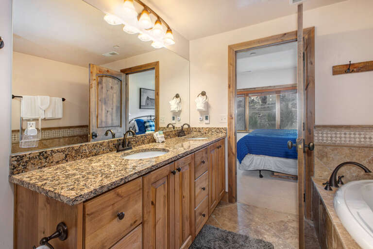 Unwind in your spacious bathroom with dual vanities, granite countertops, and warm rustic wood finishes—a perfect blend of comfort and mountain charm.