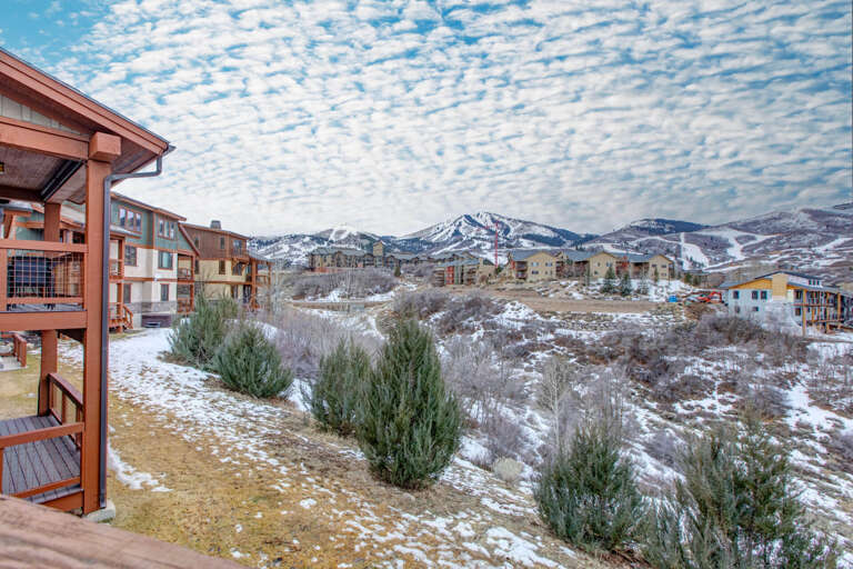 Property nestled in a scenic mountain community with snow-capped peaks and nearby ski slopes visible in the distance, offering a peaceful winter retreat setting.