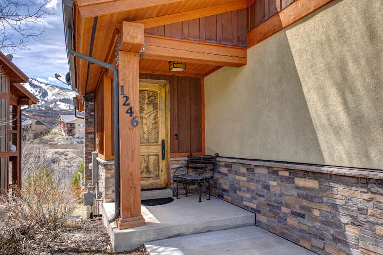 Nestled in a mountain village, this inviting entrance features warm wood and stone finishes that blend seamlessly with the alpine surroundings—an ideal retreat for your winter getaway.