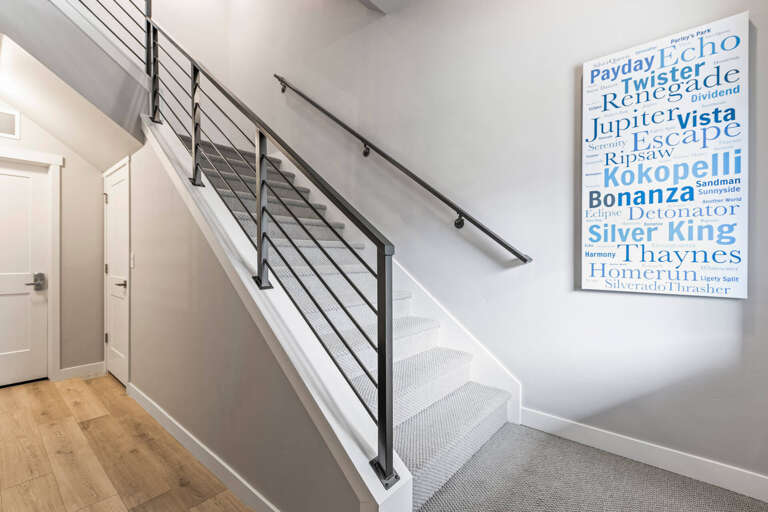 Modern staircase with contemporary metal railings leads you between floors, adorned with local coastal artwork that adds a personalized touch to your stay.