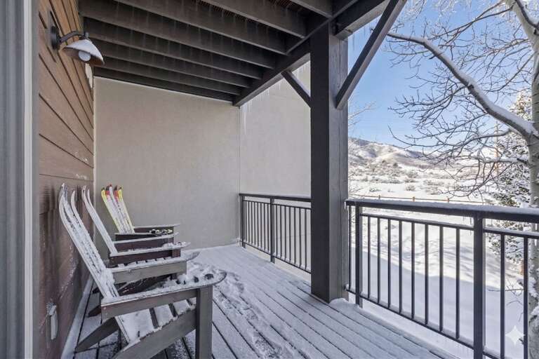 Cozy covered balcony with mountain views where you can relax in comfortable chairs while enjoying the peaceful winter landscape.