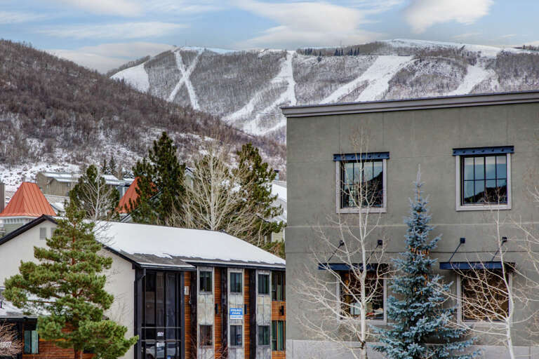 Snow-covered ski slopes with marked trails rise majestically behind the property, creating a stunning alpine backdrop for your mountain getaway.