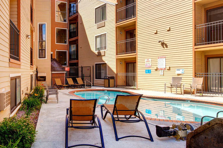 A private courtyard pool and hot tub await, surrounded by lounge chairs and mountain-style architecture. Notice boards and amenities are posted for your convenience.
