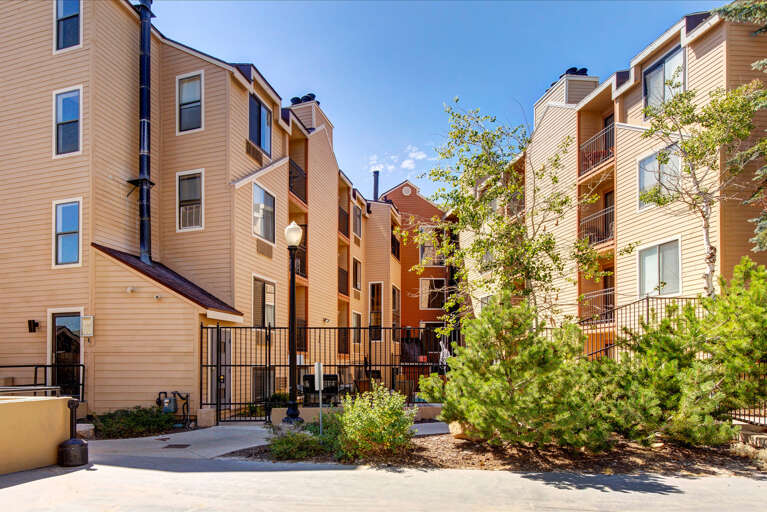 The property features multi-level buildings with balconies and landscaped courtyards, situated in a sunny residential neighborhood with convenient access.