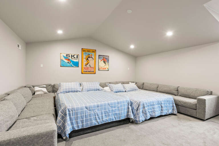 Spacious sleeping area with vintage ski posters and plush sectional seating—perfect for gathering your group after a day on the slopes.