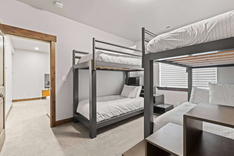 This cozy bunk room offers comfortable sleeping quarters with modern metal bunks dressed in soft linens. You'll appreciate the bright, airy space with natural light from the window and easy access to the adjoining area.