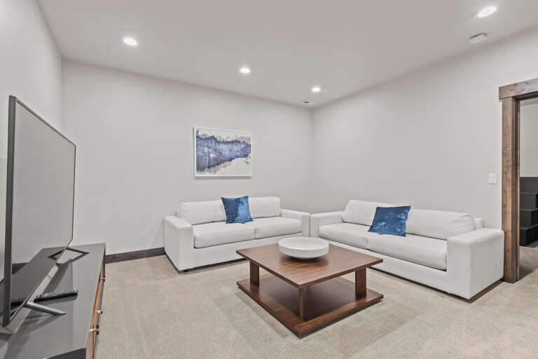 Sink into plush white sofas in your private lounge, where blue accents and warm wood tones create a serene retreat for movie nights or relaxed conversation.
