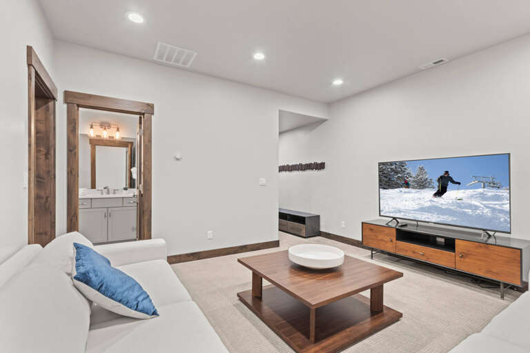 Your cozy entertainment space features plush seating, a large TV for movie nights, and warm wood accents that create the perfect retreat after mountain adventures.
