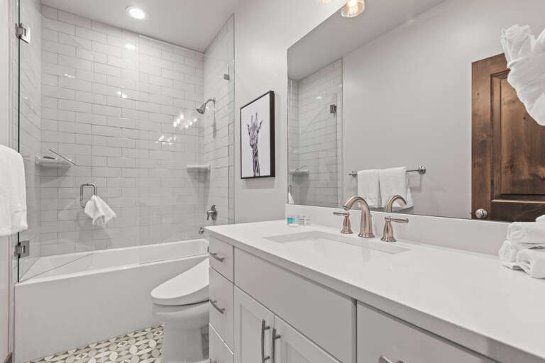 Step into your private sanctuary with gleaming white subway tiles, a soaking tub for long relaxing evenings, and plush towels waiting for you after each refreshing shower.