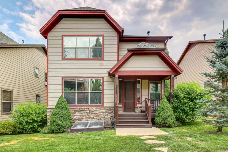Charming property exterior with red trim and stone accents, nestled in a landscaped neighborhood, providing easy identification upon arrival.