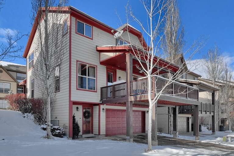 A welcoming property nestled in a quiet neighborhood, framed by bare winter trees and blanketed in fresh snow, offering easy access to the nearby mountain community.