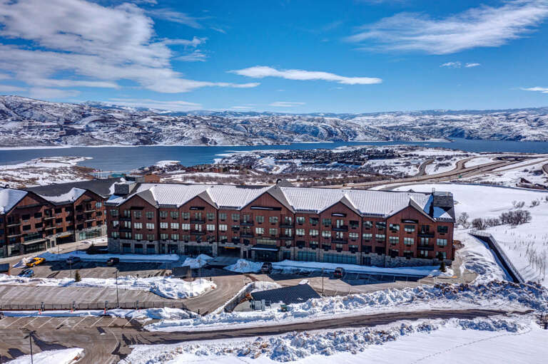 A lakeside resort property positioned against snow-covered mountains, offering scenic views of the surrounding winter landscape and nearby waterfront area.