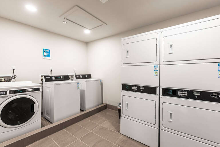 A clean, well-equipped laundry room with multiple washers and dryers ready for you to freshen up your wardrobe during your stay.