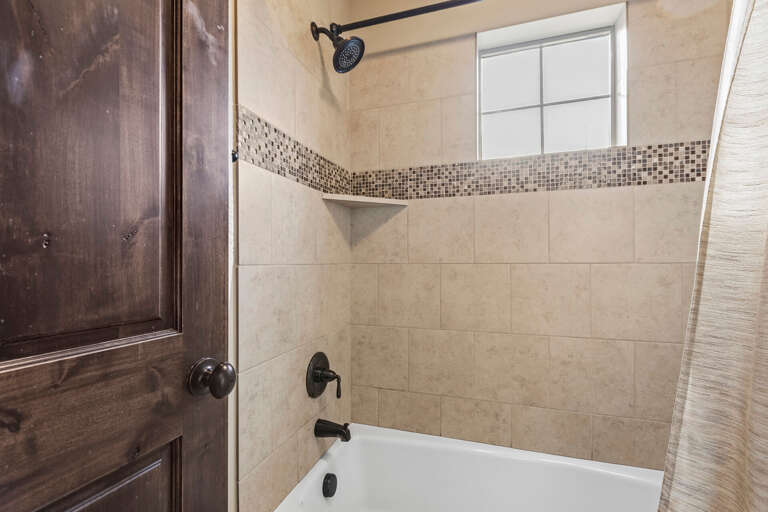 Your private bathroom features a luxurious shower-tub combo with elegant tilework and a built-in shelf for your essentials, combining comfort and style.