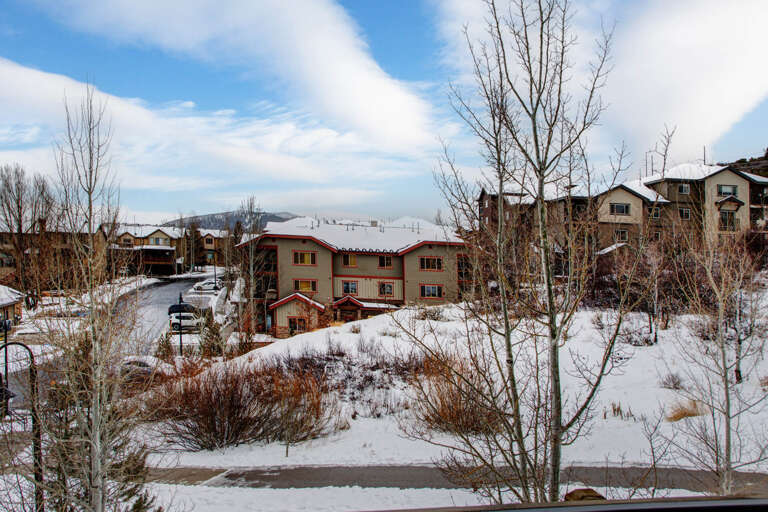 Scenic winter neighborhood with snow-covered grounds and mountain views in the distance, showcasing a peaceful residential setting surrounded by natural beauty.