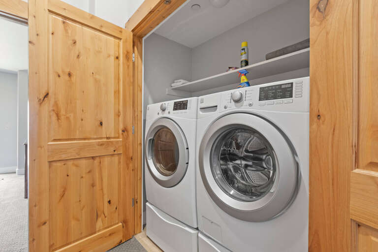 A dedicated laundry nook with full-size washer and dryer awaits, framed in warm knotty pine. No need to leave the comfort of your rental for laundry day!